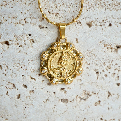 Gold krishna pendant necklace on a textured beige background