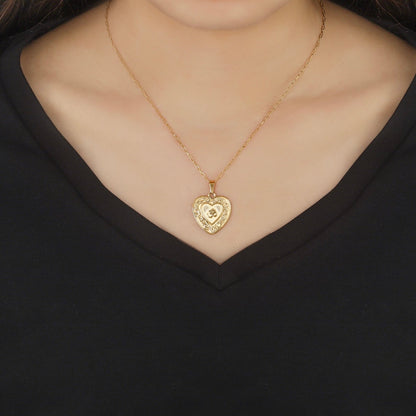 Gold heart-shaped om necklace on a black background