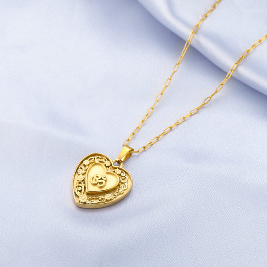 Gold heart-shaped om pendant necklace on a light blue background