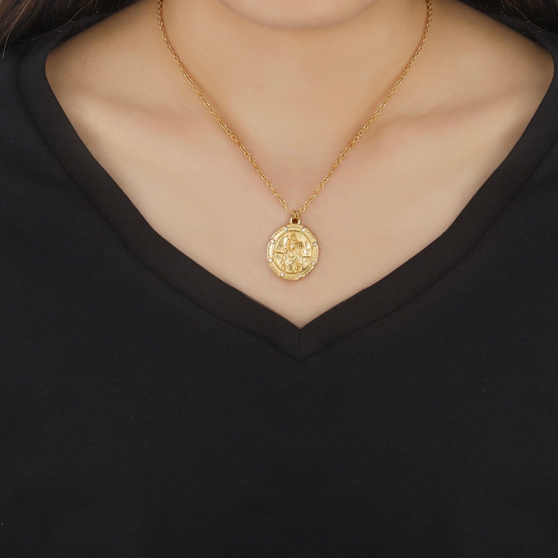 Gold shiva necklace with a pendant on a black background